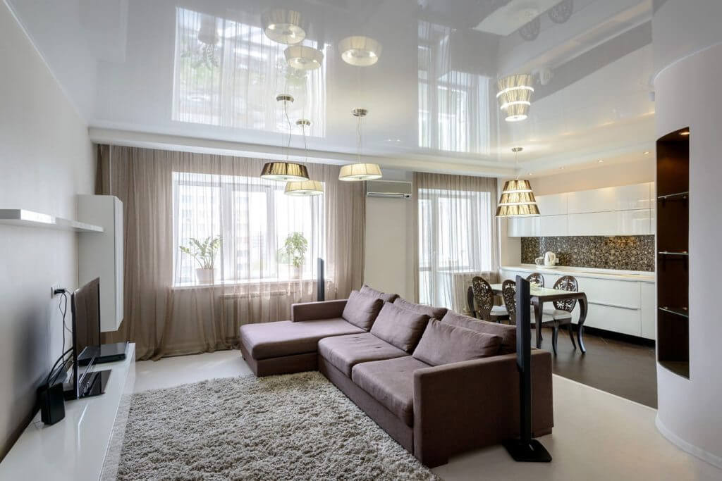 Nowoczesny salon z sufitem napinanym i zabudową ścienną