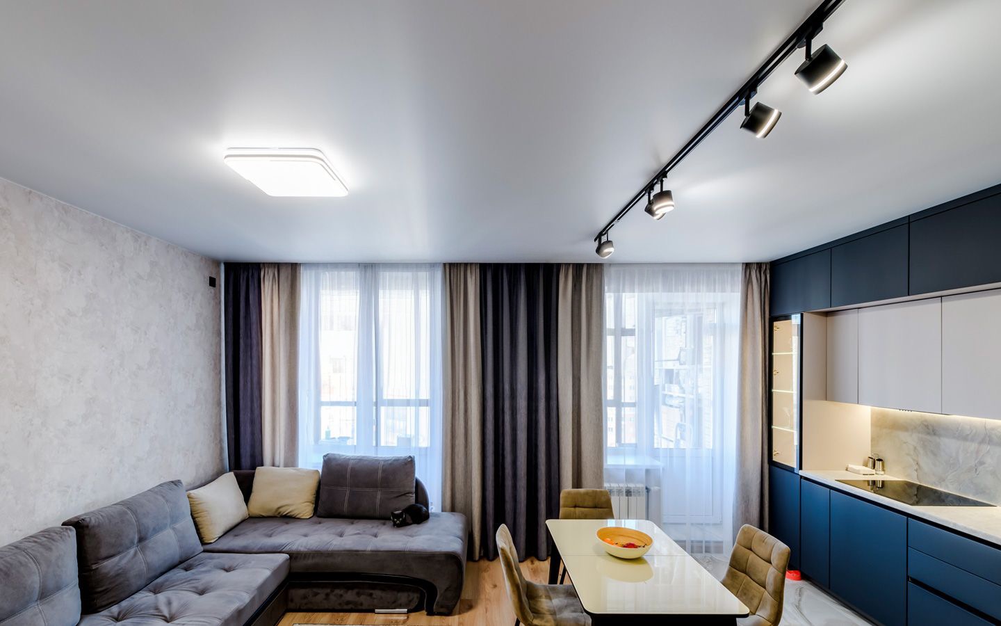 Sufit napinany w salonie z oświetleniem szynowym i lampą centralną